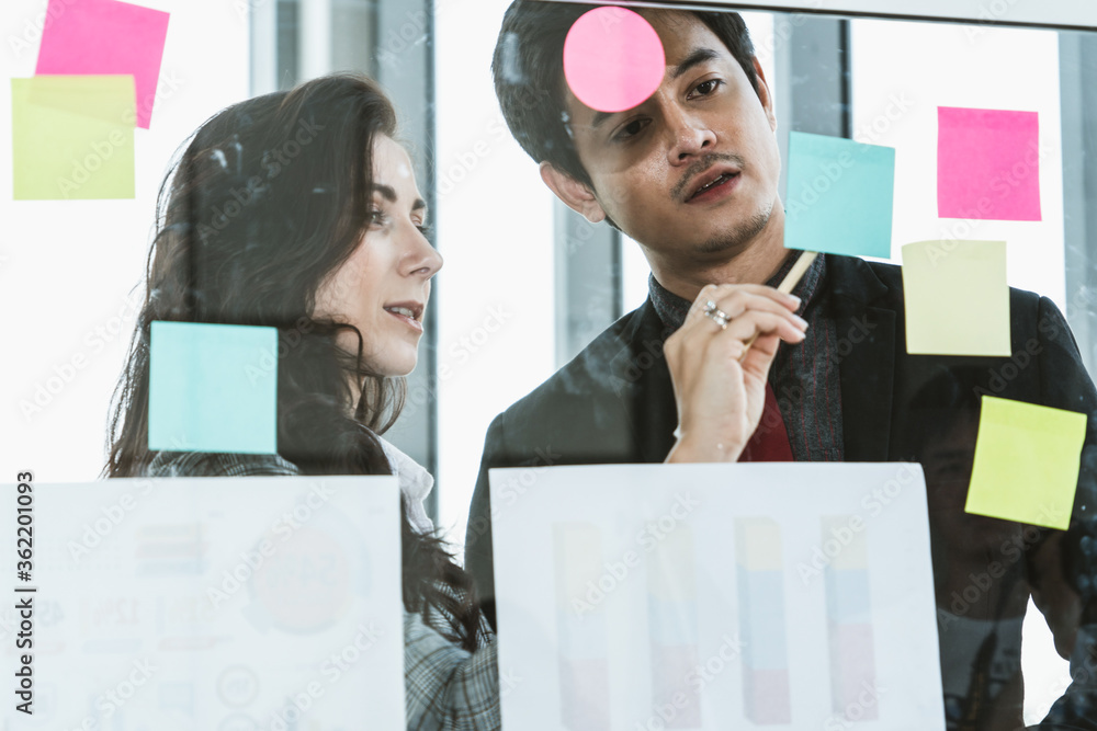 Business people work on project planning board in office and having conversation with coworker frien