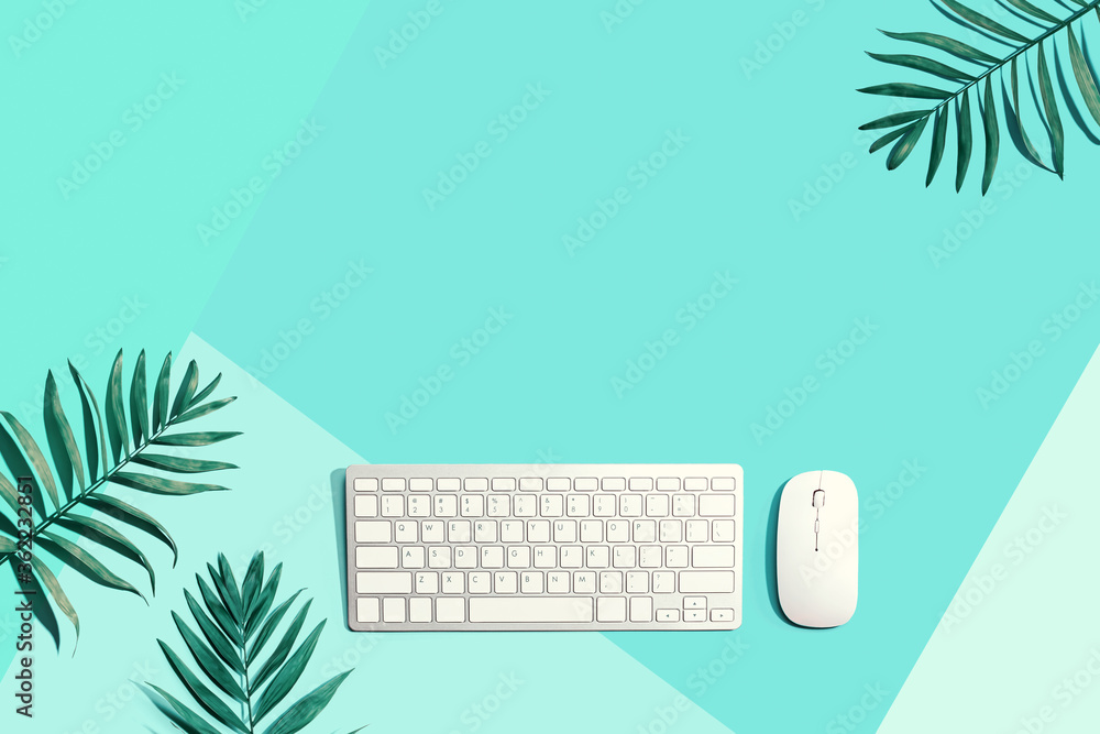 Computer keyboard and mouse with tropical leaves