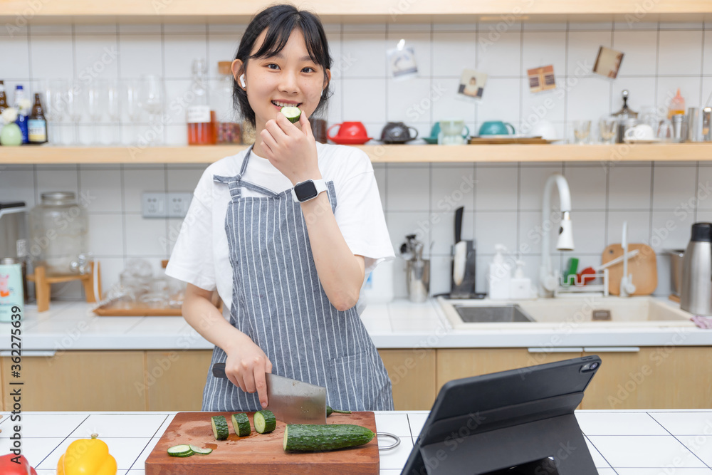 一个纯粹的女孩一边切菜一边玩平板电脑