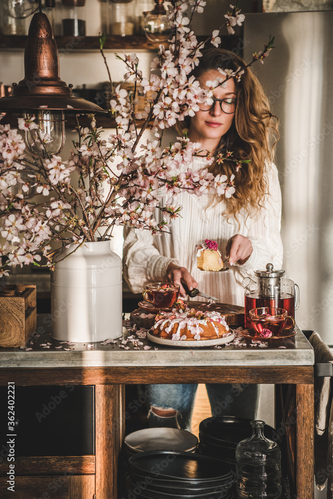 春天或夏天的茶和蛋糕。年轻的金发女人提供玫瑰和杏仁无麸质的bundt c