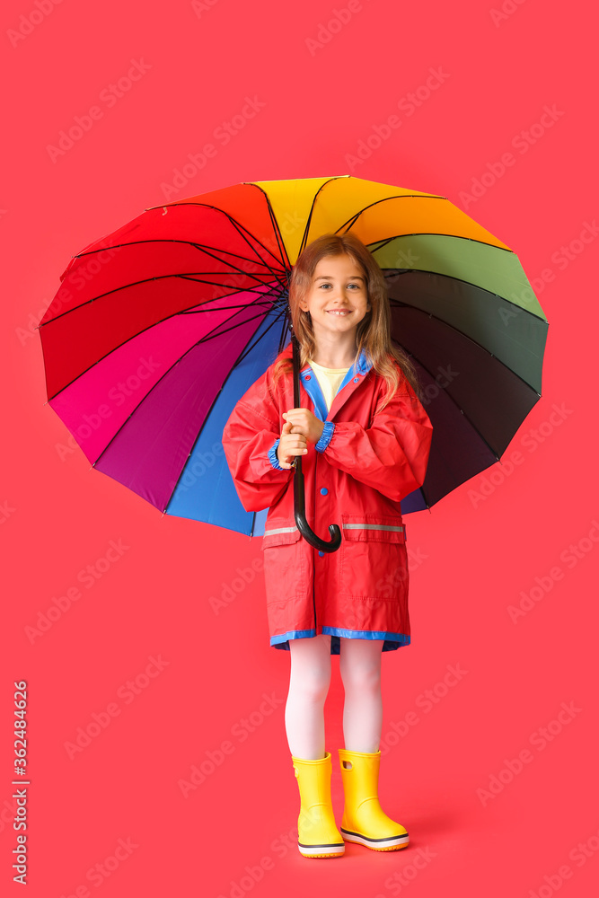 Cute little girl in raincoat and with umbrella on color background