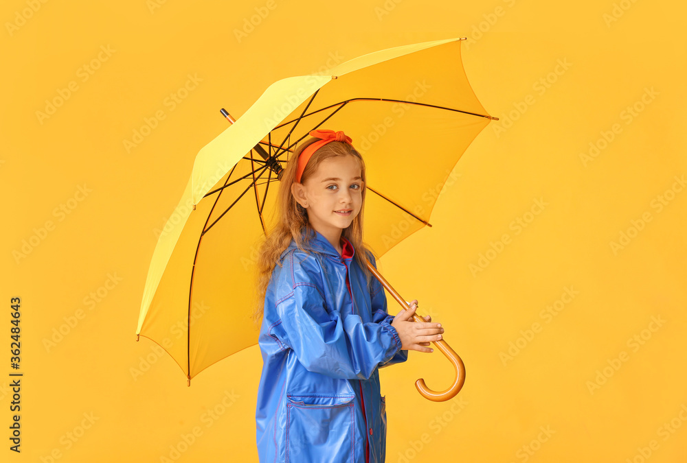 Cute little girl in raincoat and with umbrella on color background