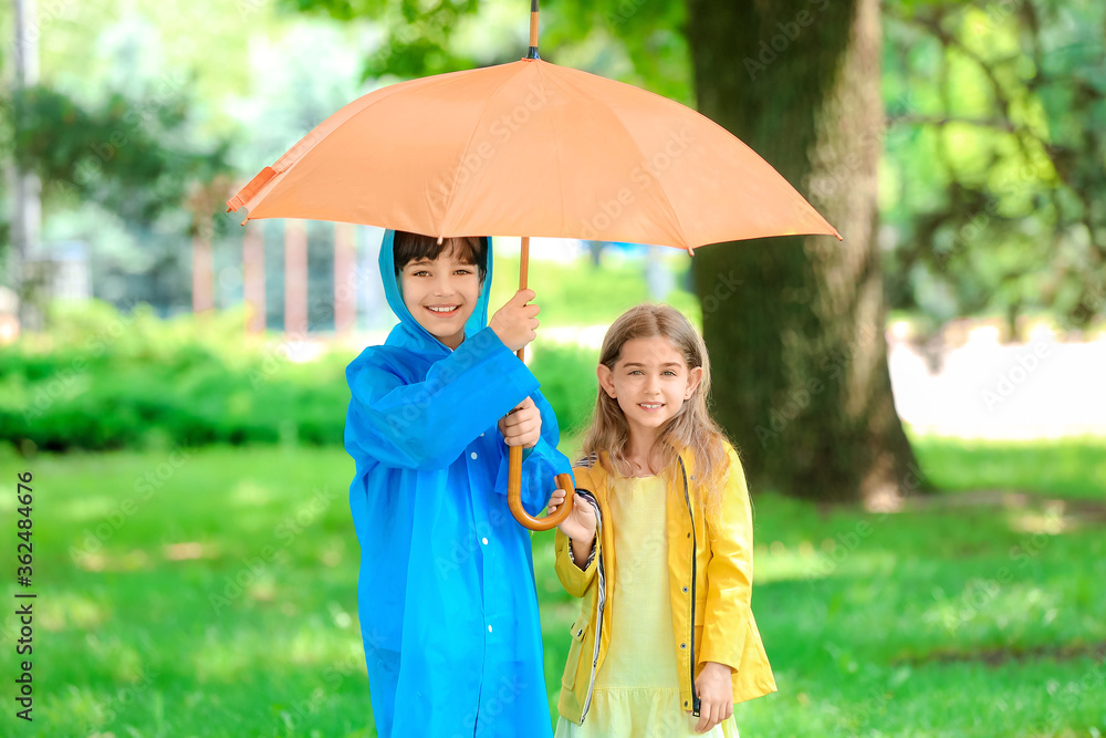 公园里带着雨伞、穿着雨衣的可爱小孩