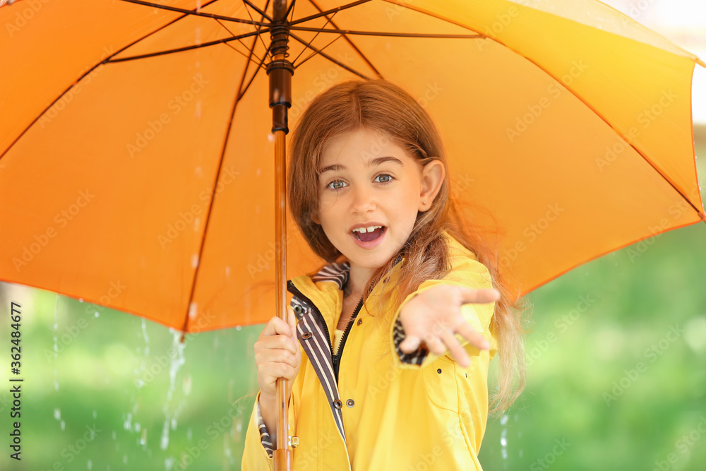 公园里带着雨伞、穿着雨衣的可爱小女孩