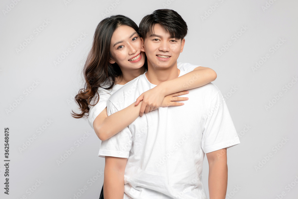 Young Asian lovers embracing in the gray background

