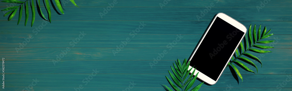 Smartphone with tropical palm leaves - flat lay