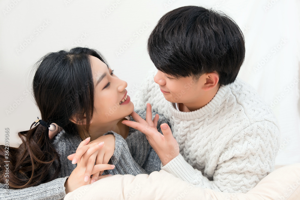 A pair of intimate young Asian lovers lying at the head of the bed