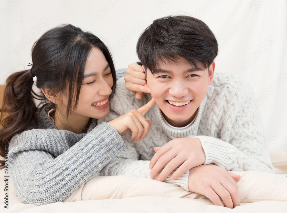 A pair of intimate young Asian lovers lying at the head of the bed

