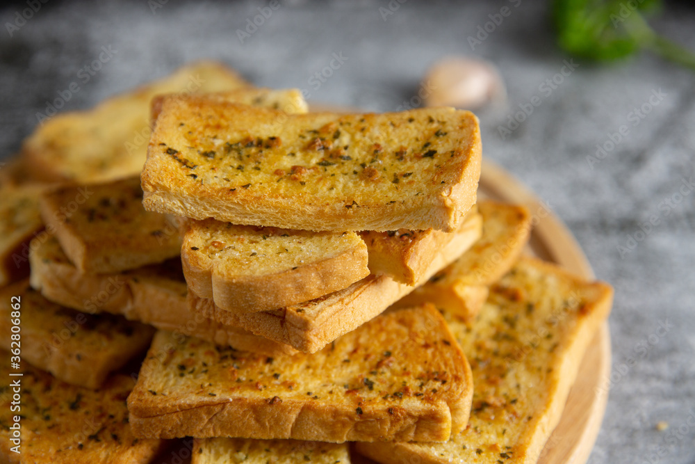 Wooden cutting board with delicious homemade garlic bread on the cement floor