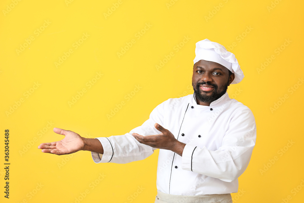 Male African-American chef showing something on color background