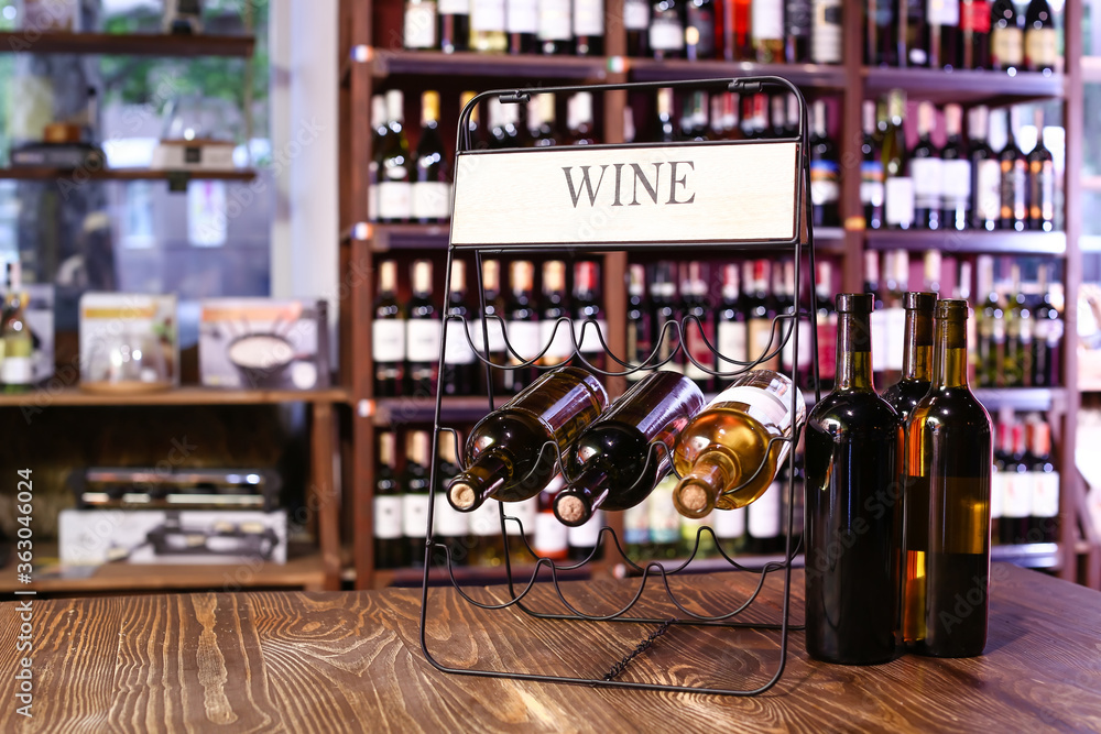 Holder with bottles of wine on table in store