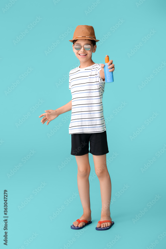 Little boy with sun protection cream on color background