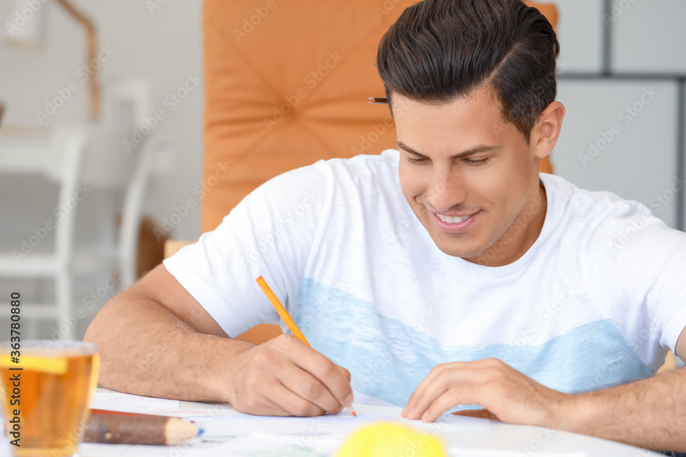 Young man coloring pictures at home