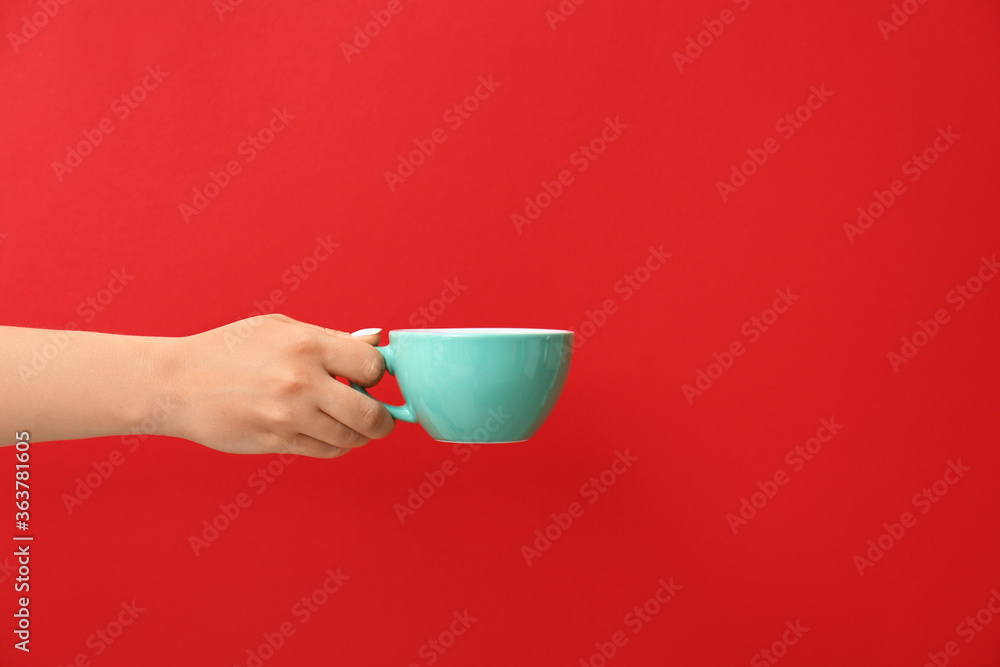 Hand with cup of hot coffee on color background