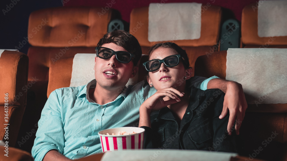 Man and woman in the cinema watching a movie with 3D glasses. with interest looking at the screen, e