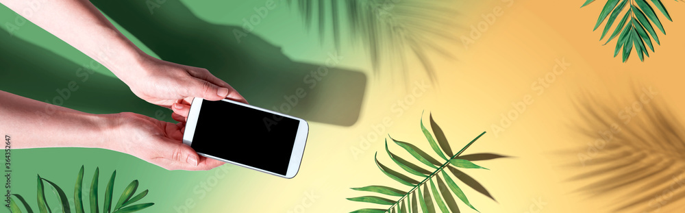 Smartphone with tropical palm leaves and shadow - flat lay