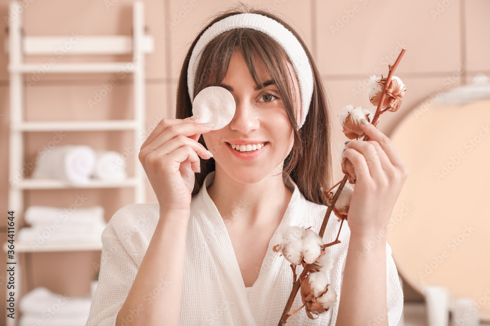 Beautiful young woman with cotton pad in bathroom