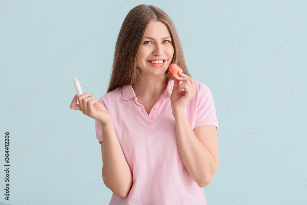 Beautiful young woman with lip balms on light background