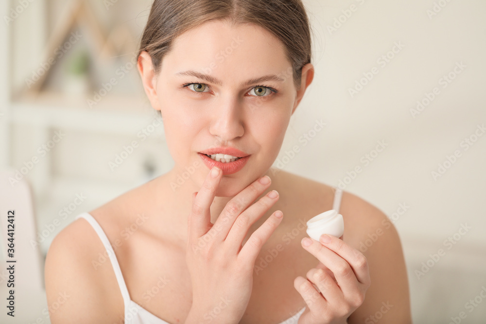 Beautiful young woman with lip balm at home