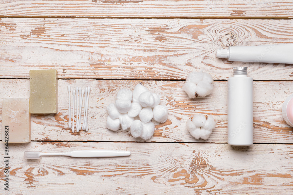 Cotton balls and cosmetics on wooden background