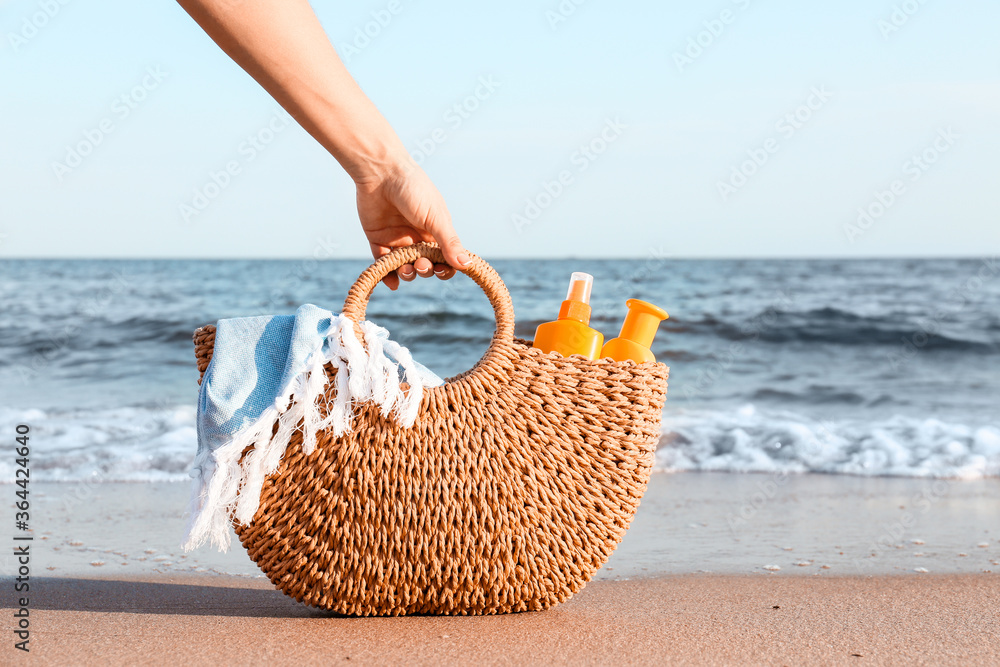 Woman with sunscreen cream in bag on beach