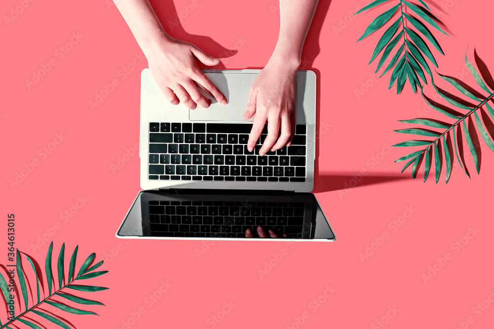 Person using a laptop computer with tropical leaves from above