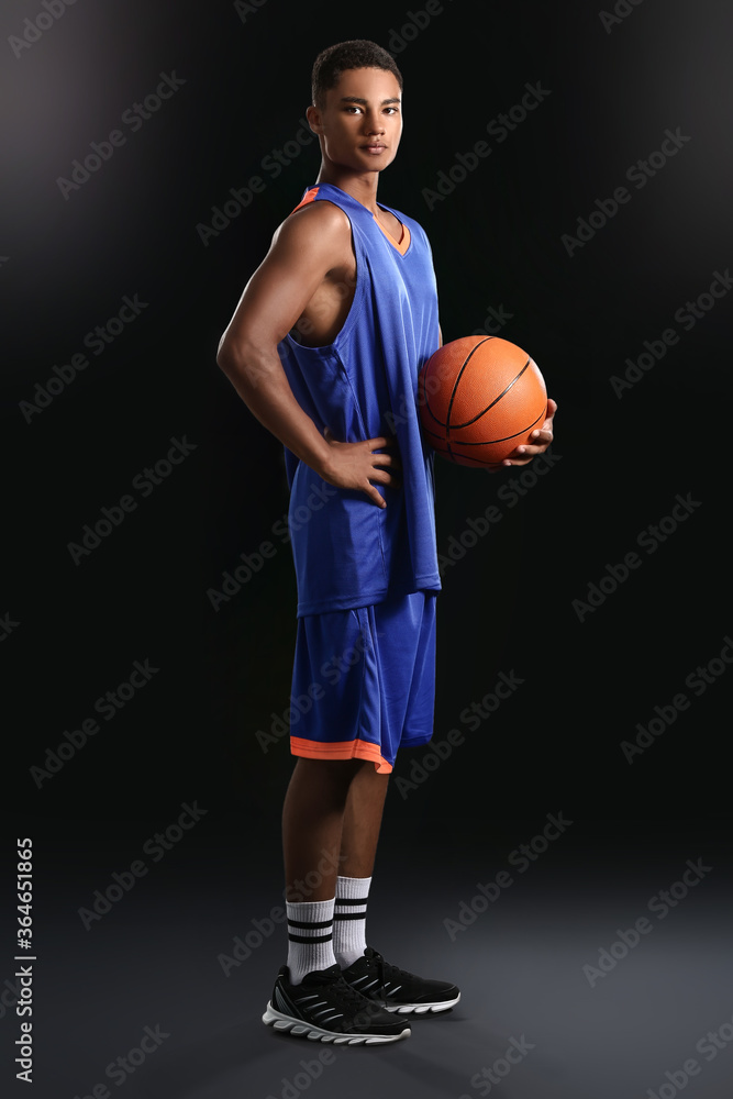 Young African-American basketball player on dark background