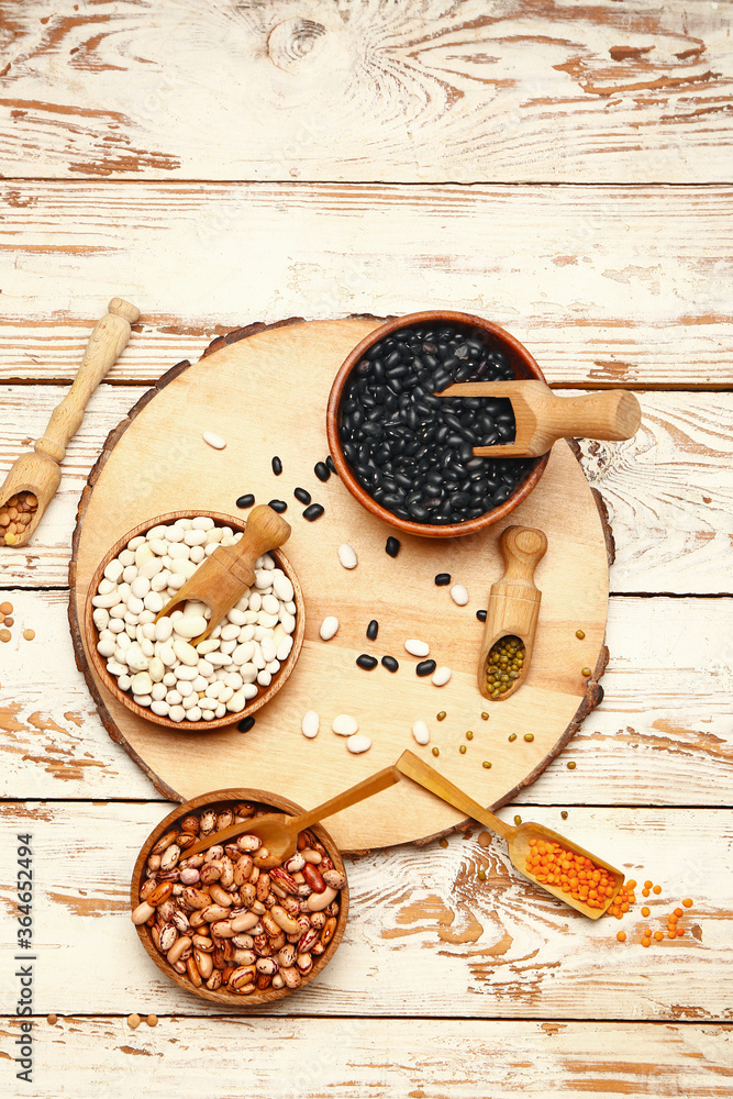 Different raw legumes on white wooden background