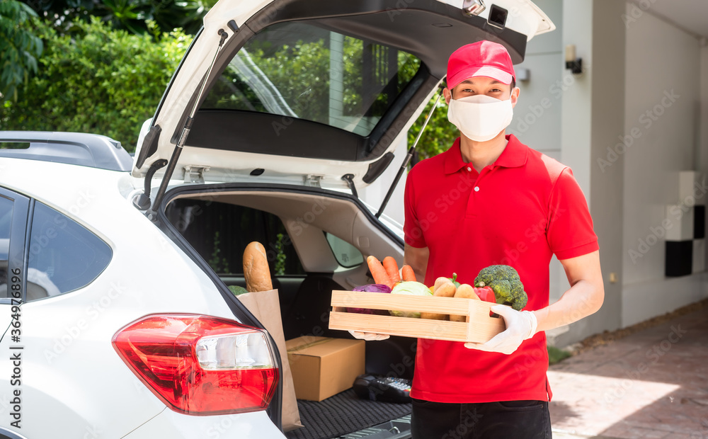 Delivery staff on red uniform holding box of fresh food delivering to customers home