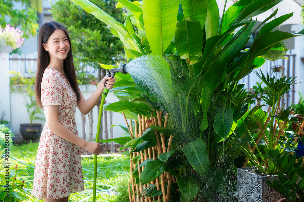 美丽的亚洲女人在花园里浇灌绿色植物的肖像