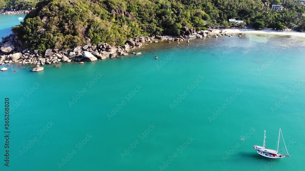 热带海岸附近的船。现代游艇在海岸附近平静的海水中航行的惊人无人机视图