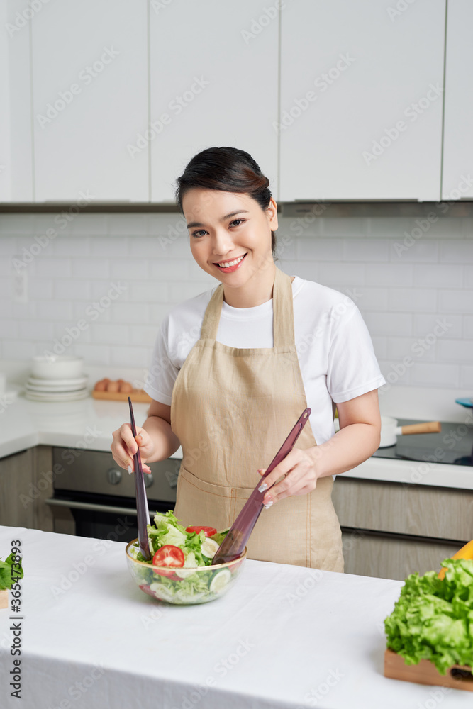 美丽的年轻女子正在厨房准备蔬菜沙拉