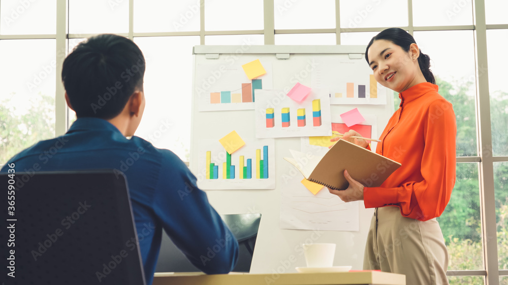 Young woman explains business data on white board in casual office room . The confident Asian busine