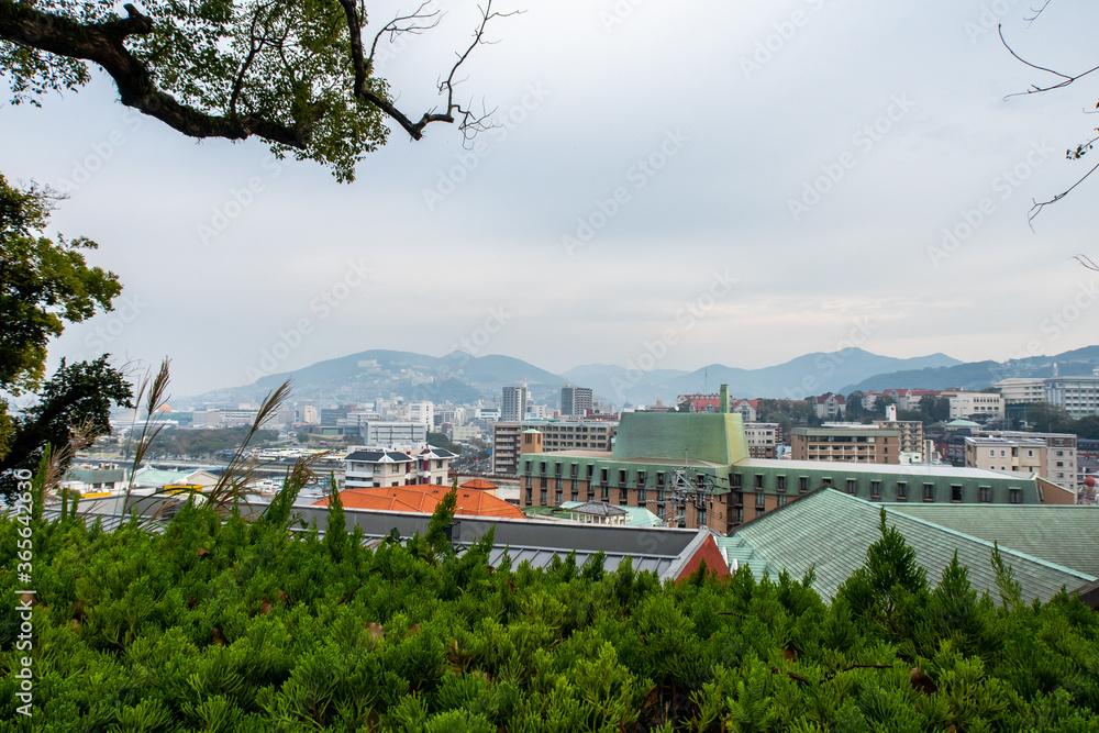 日本长崎。从格洛弗花园看到的长崎风景，秋天的树木和阴天