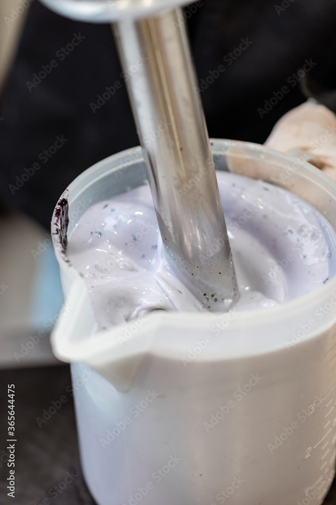 Chef blending milk with blueberries, preparing base for ice cream production, close-up