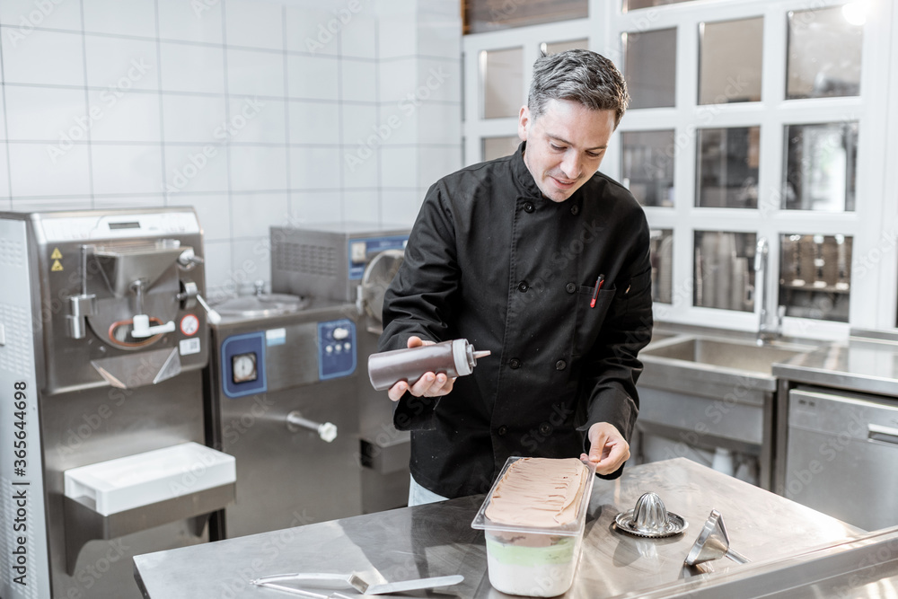 Confectioner pouring chocolate on the ice cream, making ice cream on the kitchen of a small manufact