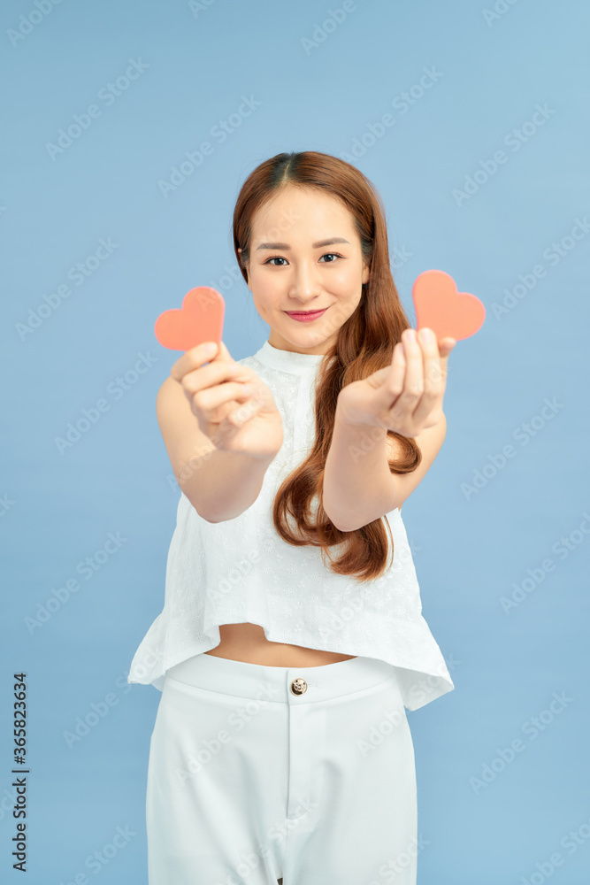 Portrait of thoughtful ponder girl in good mood having two little small red paper carton hearts in h