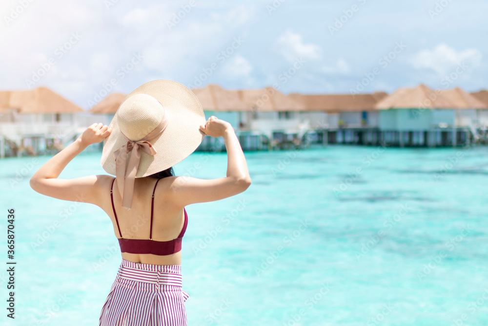 年轻女孩戴着帽子在美丽的绿松石海水中行走。tro的快乐旅行者