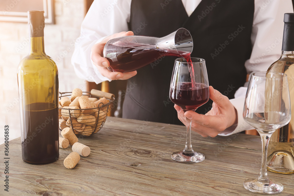 Sommelier pouring wine from decanter into glass in cellar