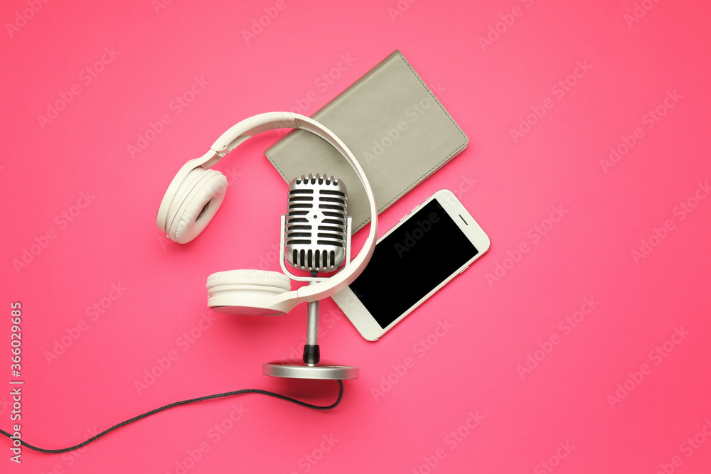 Headphones with microphone, mobile phone and notebook on color background