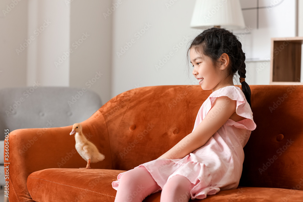 Little girl with cute duckling at home