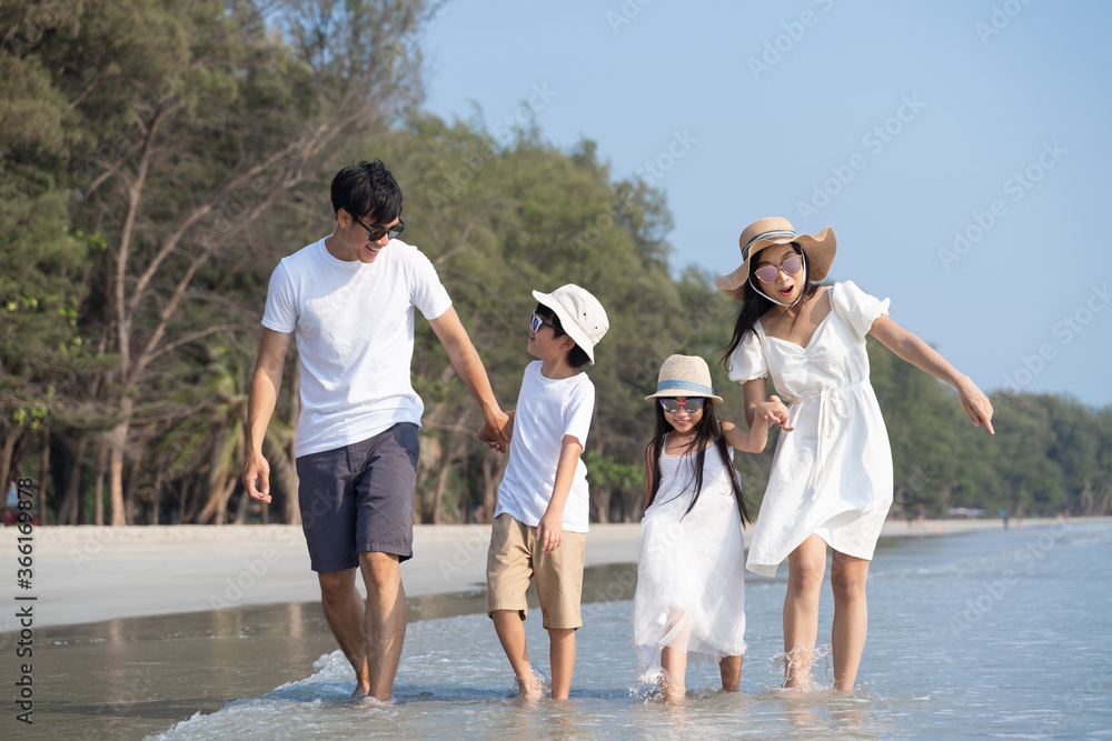 亚洲家庭带着孩子在海滩散步快乐度假概念