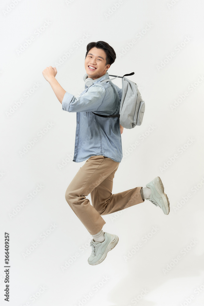 Full length portrait of a funny cheerful male student jumping on white background