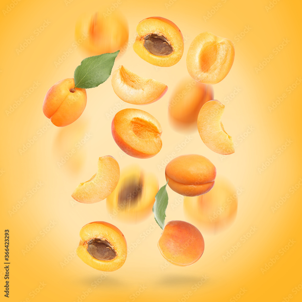 Falling ripe apricots on color background