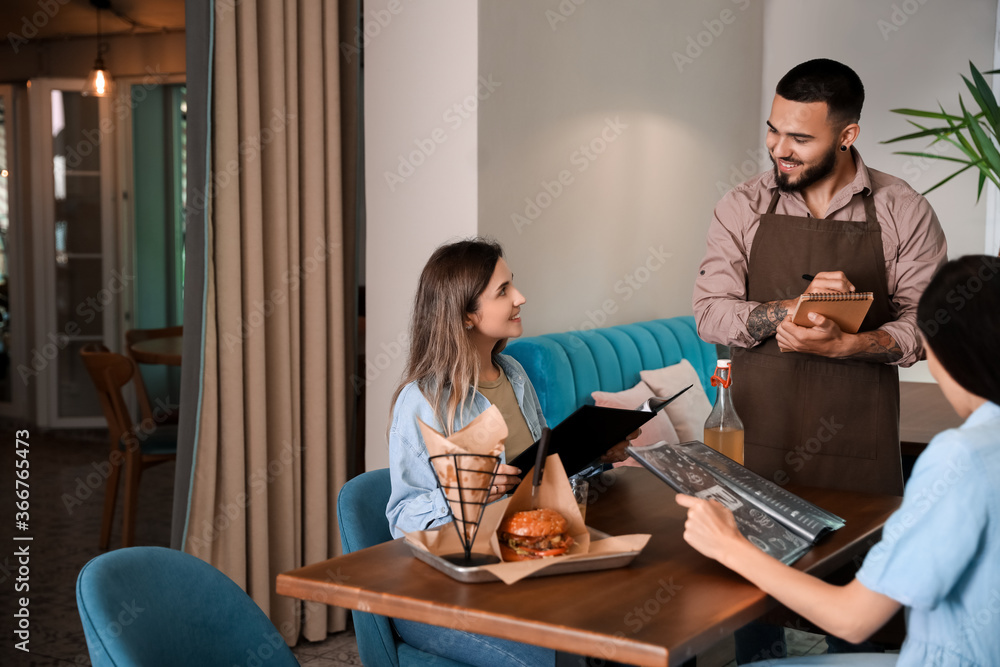 Waiter serving clients in restaurant