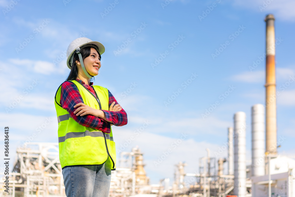 Asian woman engineer arm crossed and smile with confident looking forward to future with oil refiner