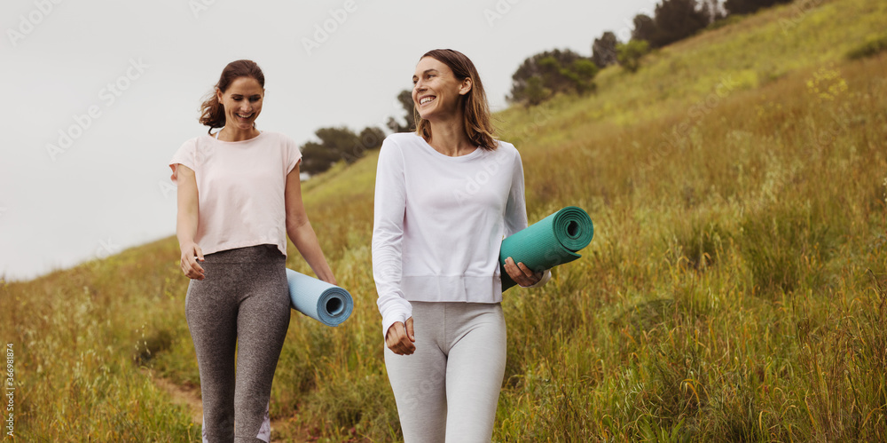 健身女性手持瑜伽垫在户外行走