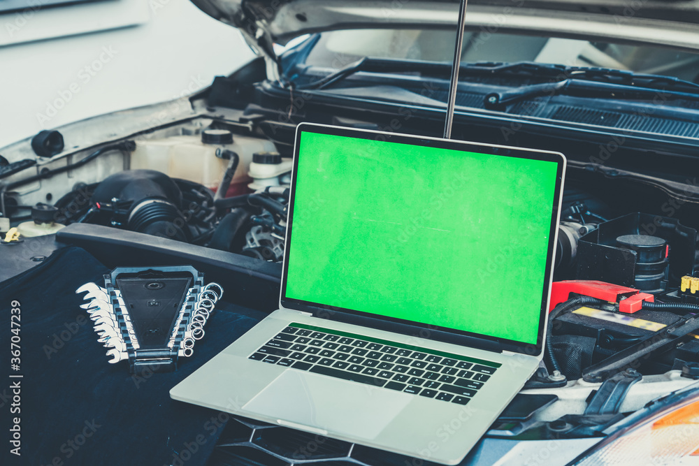 Laptop computer on car hood for engine diagnostic. Car garage repair service concept.