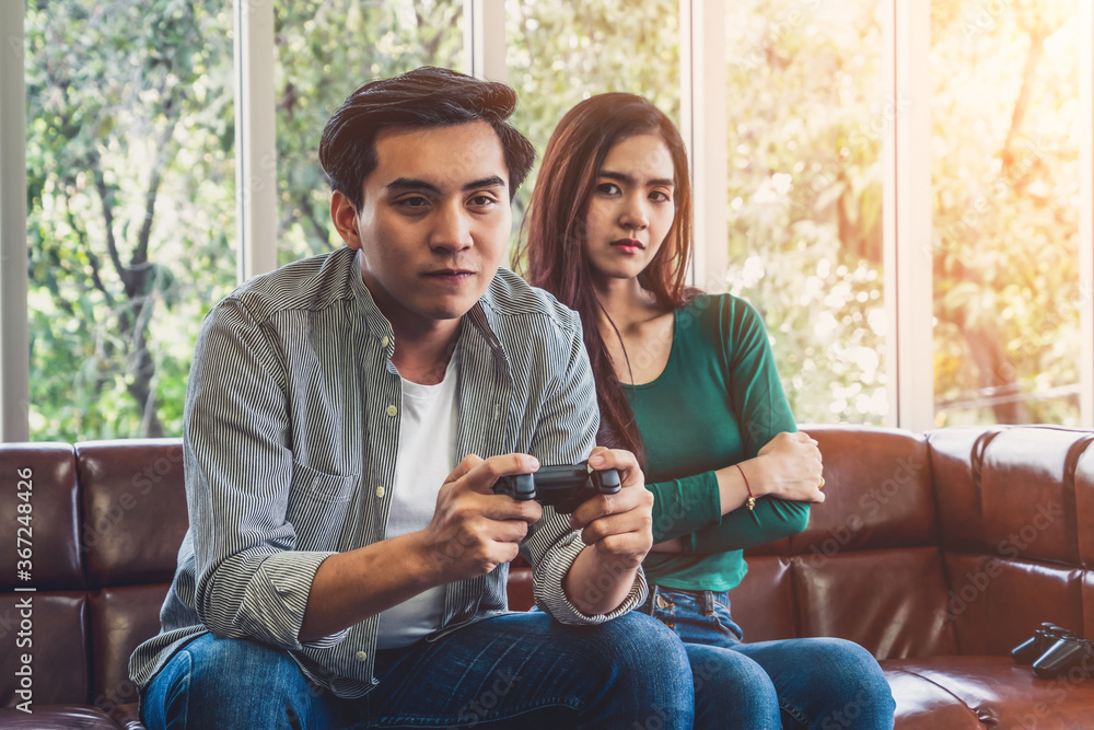 Young Asian couple suffers from computer games addiction. Family problem concept.