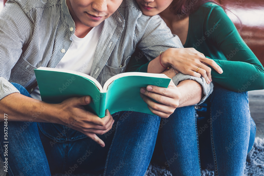 Young Asian couple reading book in living room. Love relationship and lifestyle concept.